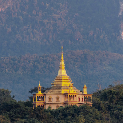 Beautiful Buddhist temple on the hill around with forest and big mountain background, Wat Pa Phon Phao at Luang Prabang, Laos, Asia