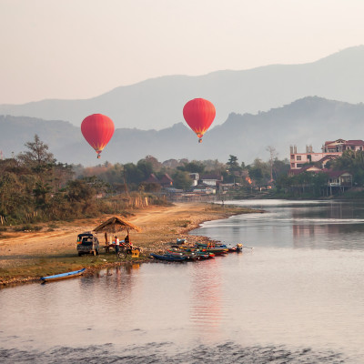 Concept recreation: hot air balloons flying over the river Nam Song at sunrise. Vang Vieng, Laos, Asia