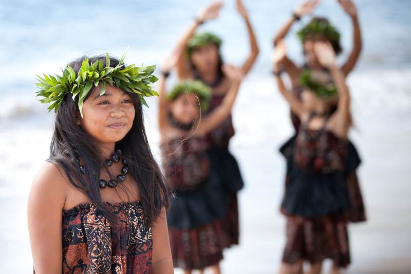 Hula girl on the beach with her fellow dancers behind her