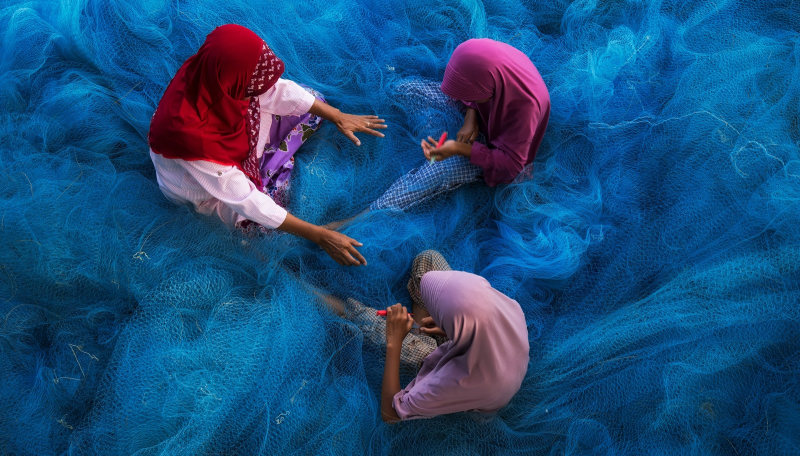 Woman are repairing blue fishing net-oman